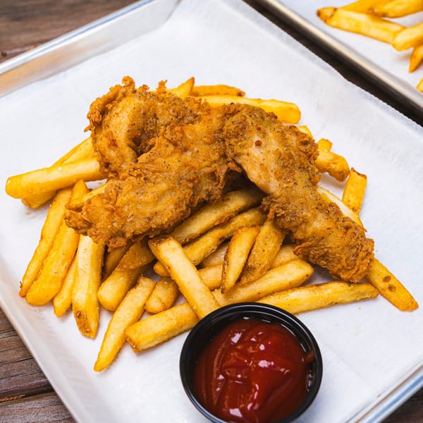 Golden fried chicken tenders and french fries with a side of ketchup on a metal tray.