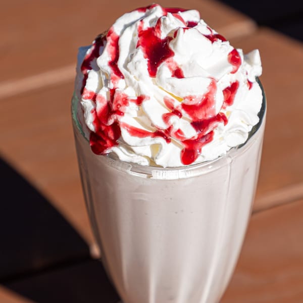 A Fryer's Roadside milkshake topped with whipped cream and drizzled with red syrup.