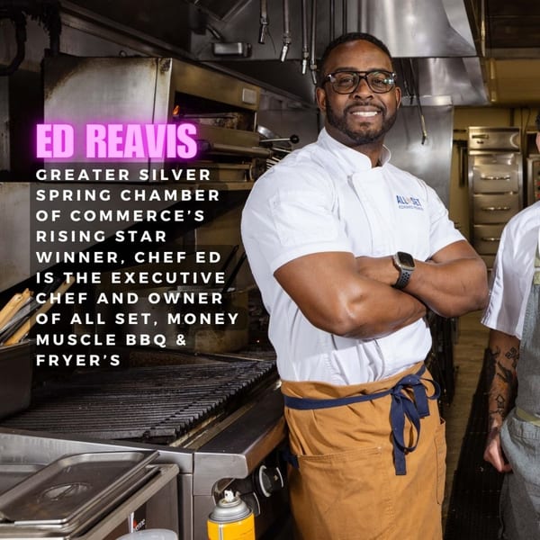 Chef Ed Reavis, owner of Fryer's Roadside, smiles in a professional kitchen with arms crossed.
