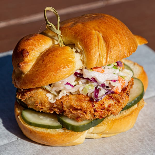 Fryer's Roadside fried chicken sandwich with coleslaw and pickles on a brioche bun.